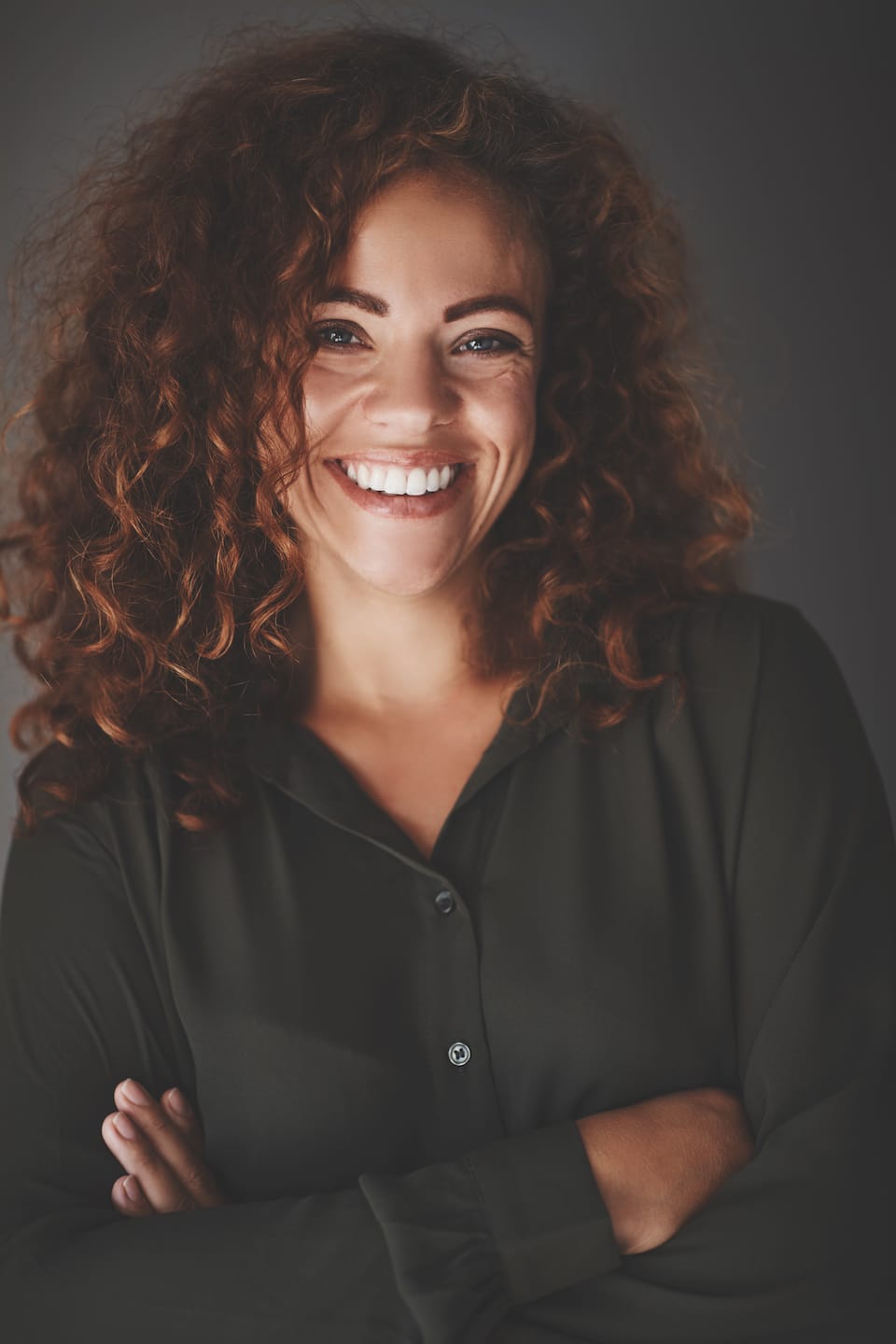 smiling-businesswoman-standing-with-arms-crossed-ULM4PGT