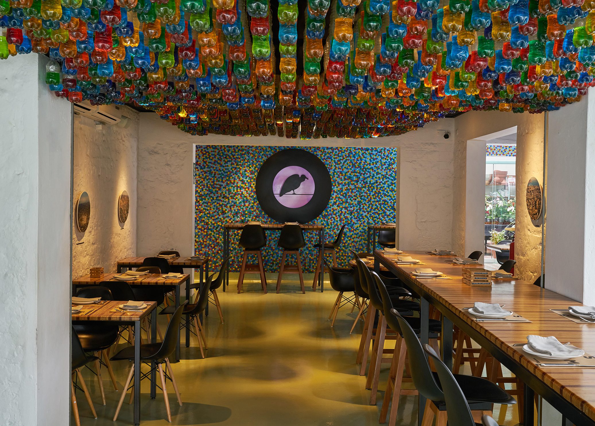 cosme_dinner Cosme Dinner with bottle caps around the logo wall on the back and color bottles on top | Photo by Cosme