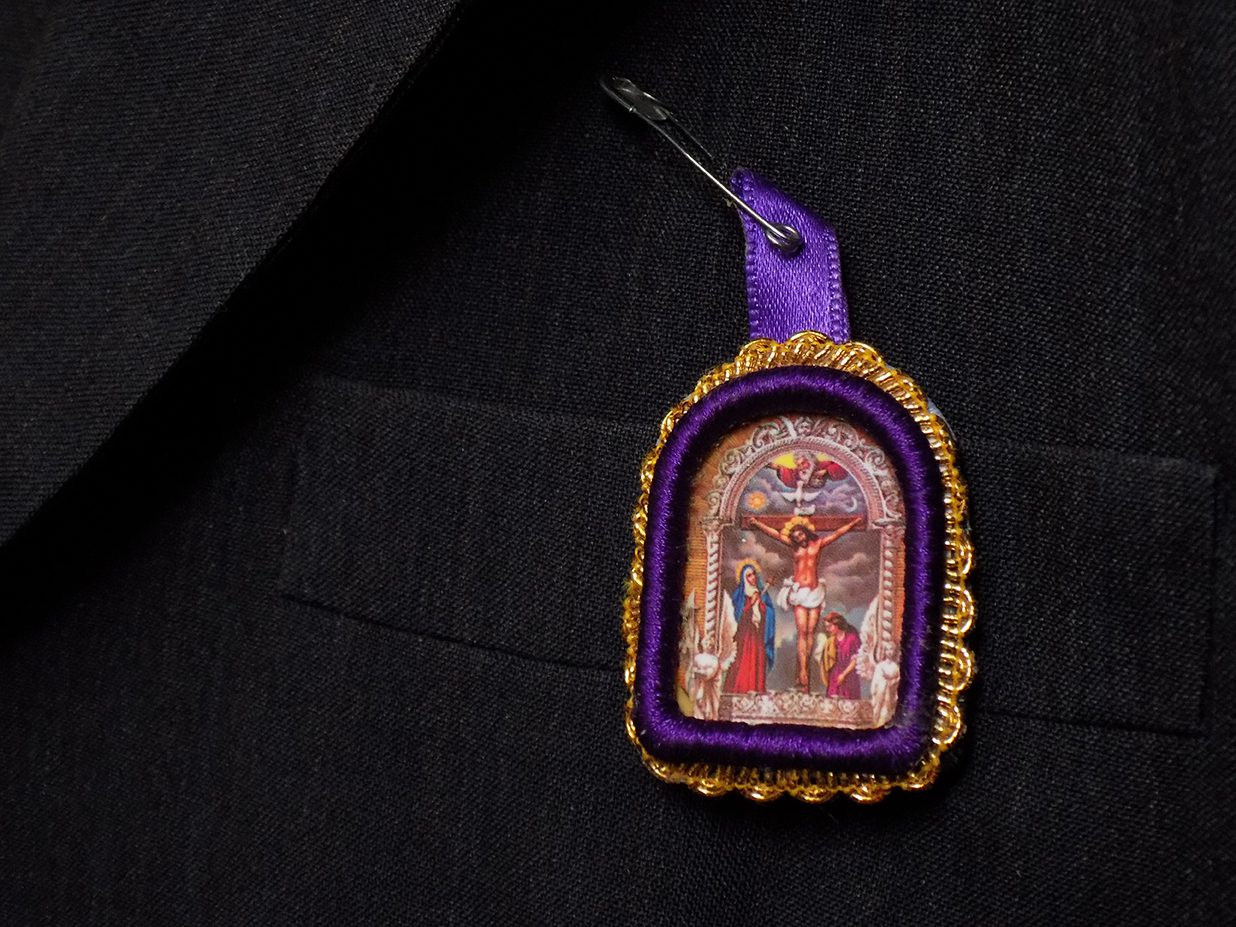 Imagen del Señor de los Milagros colgada sobre solapa de traje Imagen del Señor de los Milagros colgada sobre solapa de traje Photo by Adobe Stock
